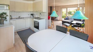 A modern kitchen with white cabinets, a built-in oven, and a dining area with a round table and chairs. - 2 bedroom beautiful home in Samsø (Samsø)