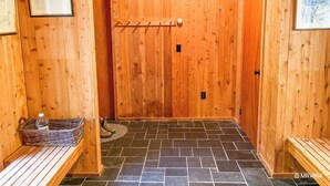 Un sauna de madera con bancos, un banco con una cesta y un perchero.