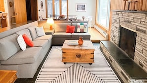 Una sala de estar moderna con un sofá seccional gris, una mesa de centro de madera y una chimenea.