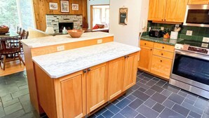 Una cocina moderna con armarios de madera, una chimenea de piedra y una isla grande.