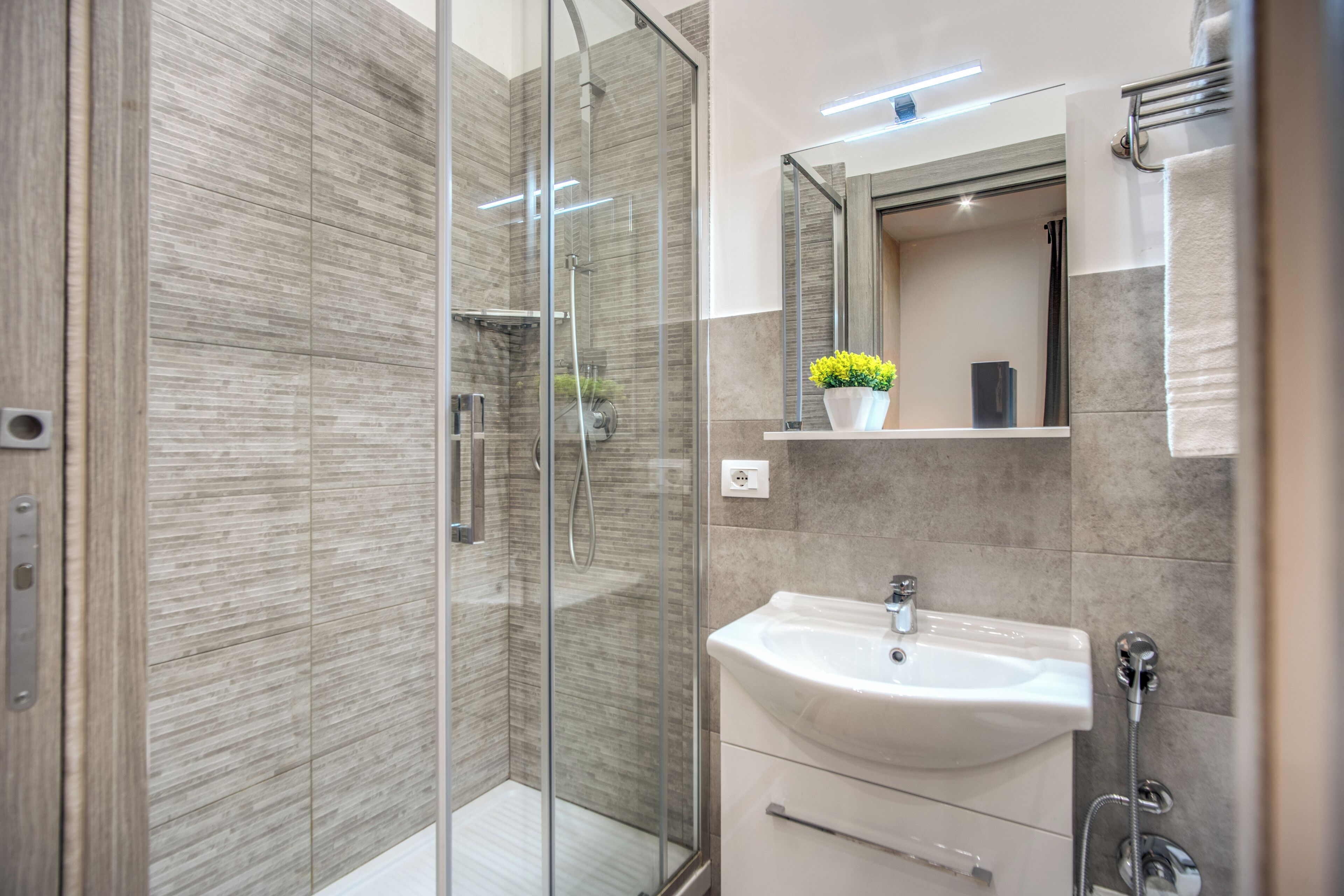 Un baño moderno con cabina de ducha de vidrio, un lavabo blanco y un espejo encima.
