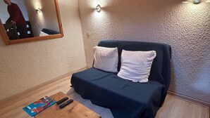 A small, cozy room with a bed, a wooden table, and a mirror on the wall. - Quiet apartment with parking, near Portes du Soleil (Abondance)