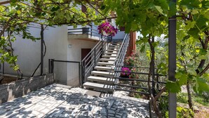 A stone staircase leading to a building with a metal railing, surrounded by greenery and flowering plants. - Cozy apartment in Rijeka with WiFi (Rijeka)