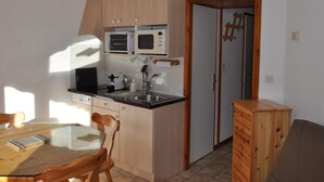 Une cuisine de taille réduite, dotée de meubles en bois, d’un four à micro-ondes, d’un grille-pain et d’un évier.