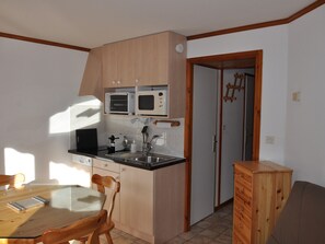 A compact kitchen with wooden cabinets, a microwave, a toaster, and a sink.