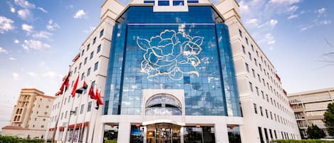 Un hotel moderno con una amplia fachada de vidrio, una entrada central y varias banderas.