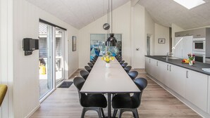 A modern kitchen with a long dining table, black chairs, and a central vase with flowers. - Stunning home in Samsø with sauna (Samsø)