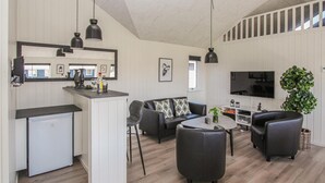 A modern living room with a kitchen area, a dining table, and a TV. - Stunning home in Samsø with sauna (Samsø)