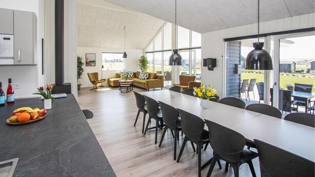 A spacious living area with a long dining table, comfortable seating, and large windows offering a view of the outdoors. - Stunning home in Samsø with sauna (Samsø)