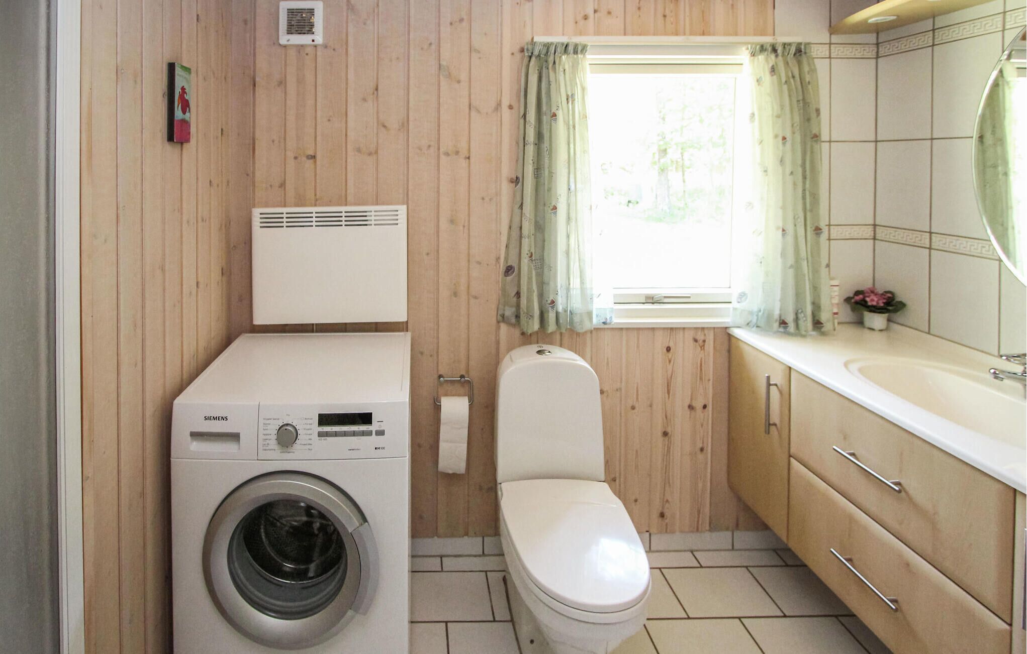 A compact bathroom with a washing machine, toilet, and sink.