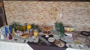 Una mesa de buffet con diversos alimentos y salsas, un reloj y una pared con textura.