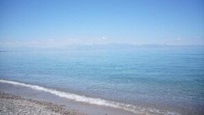 Un mar tranquilo con cielo despejado y montañas a lo lejos.
