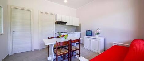 A compact living space with a kitchenette, a dining area, and a bed.