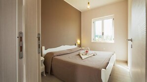 Un dormitorio con cama, mesita de noche y ventana.