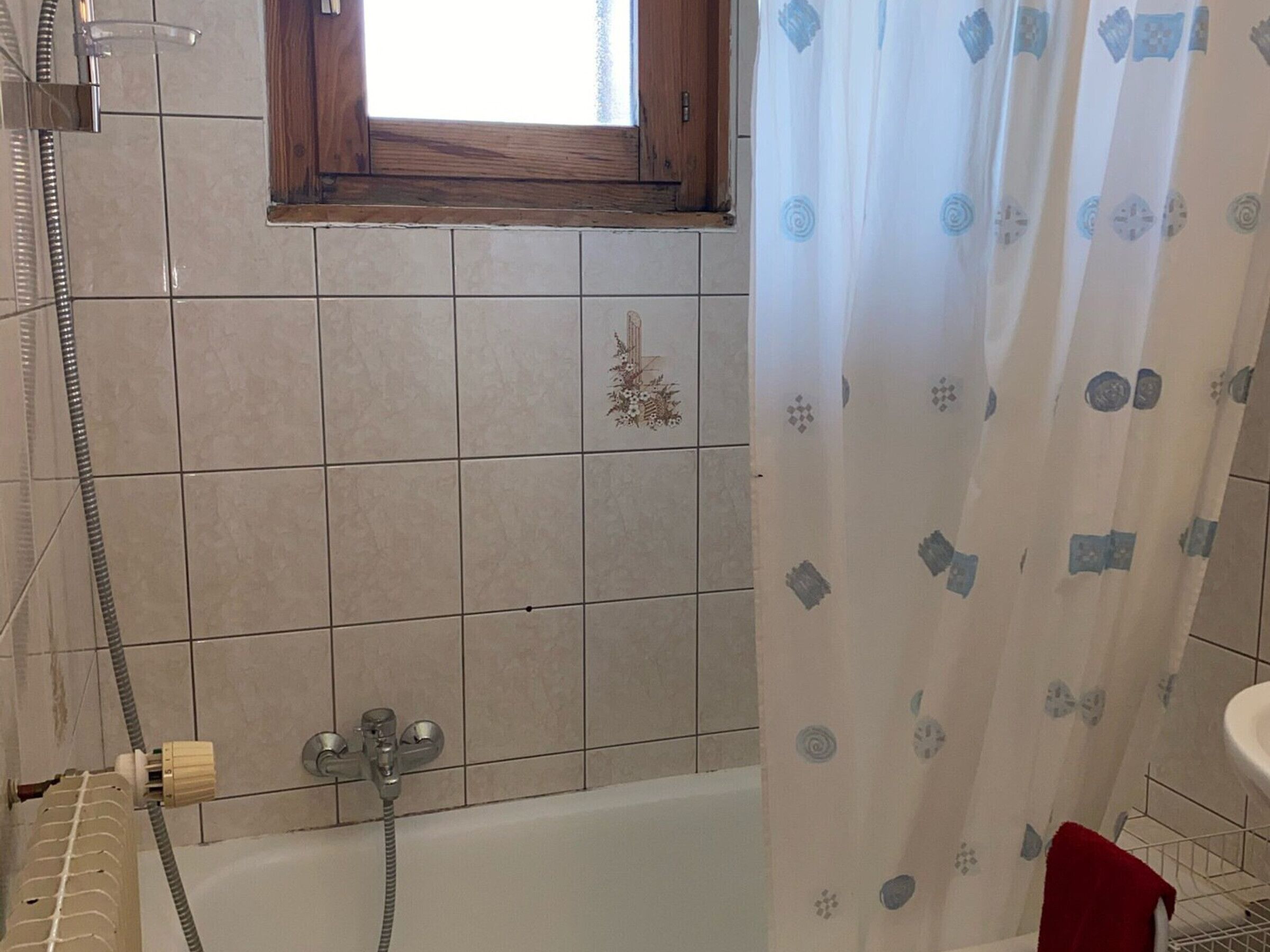 Ein Badezimmer mit einer Badewanne, einer Dusche und einem Fenster über der Wanne.