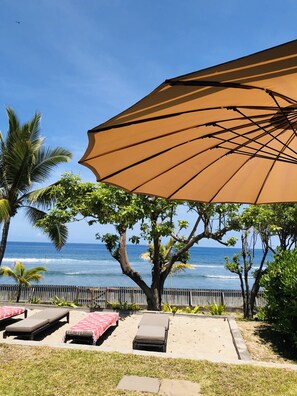 A beachside lounge area with a large umbrella, lounge chairs, and a view of the ocean. - SAINT GILLES LES BAINS, Waterfront, seaside Maison BALEINES, 4 **** (Saint Paul)