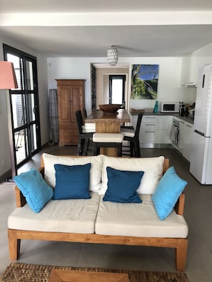 A modern living room with a sofa, a dining table, and a kitchen area. - SAINT GILLES LES BAINS, Waterfront, seaside Maison BALEINES, 4 **** (Saint Paul)
