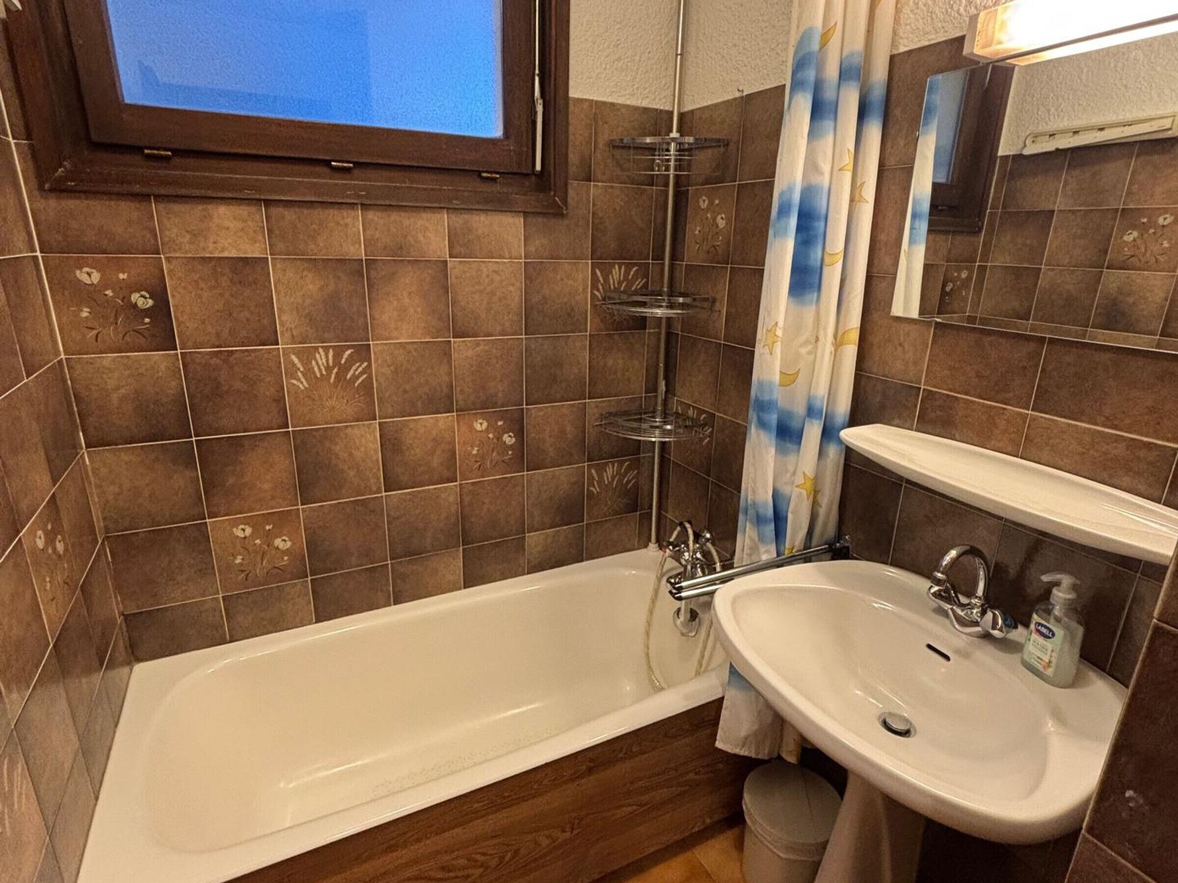 Et badeværelse med badekar, håndvask, brusebad og et vindue.
