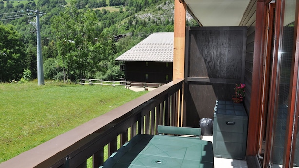 Uma varanda com vista para uma paisagem verde e uma montanha ao fundo.