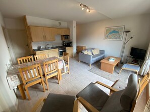 Un espacio habitable compacto con cocina, comedor, sofá y televisor.