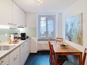 Uma cozinha compacta com área de refeições, uma janela com cortinas e um quadro na parede.
