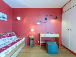 Ein Schlafzimmer mit Bett, Nachttisch, Lampe, Schreibtisch und Kleiderschrank.