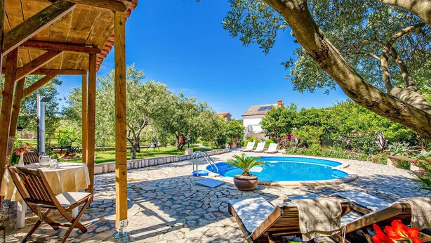 A pool area with lounge chairs, a pergola, and a stone patio.