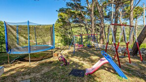 A playground with a trampoline, swings, and slides.