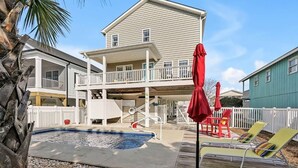 Une maison à deux étages avec un balcon, une piscine et un espace salon extérieur.