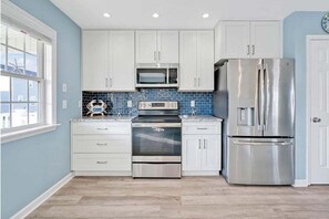 A kitchen with white cabinets, a stainless steel refrigerator, a microwave, and an oven.