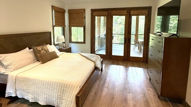 Ein Schlafzimmer mit einem großen Bett, Holzboden, einem Schminktisch und einem Fernseher.