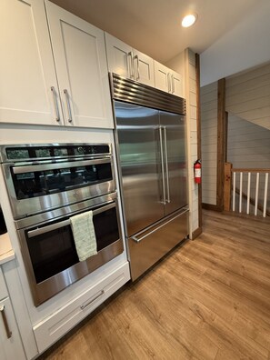 Une cuisine équipée d’appareils électroménagers en acier inoxydable, de meubles blancs et d’un plancher en bois.