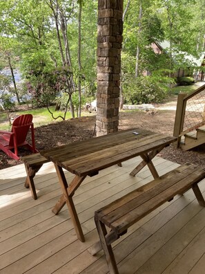 Relax on the outdoor deck with comfortable seating for two, surrounded by a serene natural landscape.