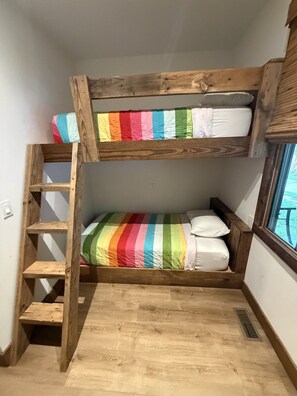 Un lit superposé avec une couverture à rayures arc-en-ciel et une échelle en bois.