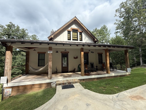 A two-story house with a covered porch, a front door, and a small front yard.