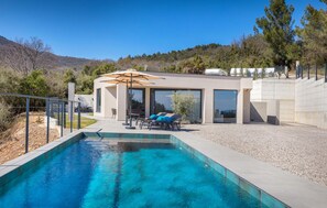 Relax by the pool in a serene natural setting, surrounded by hills and trees.