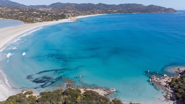 An aerial view of a coastal area with a beach, clear blue waters, and surrounding hills. - Cozy apartment in Quartu Sant'Elena with WiFi (Quartu Sant'Elena)