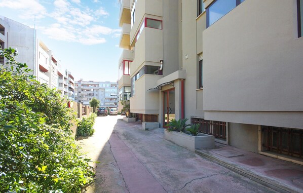 A narrow urban street lined with multi-story residential buildings, featuring balconies and large windows. - Amazing apartment in Quartu Sant'Elena with WiFi (Quartu Sant'Elena)