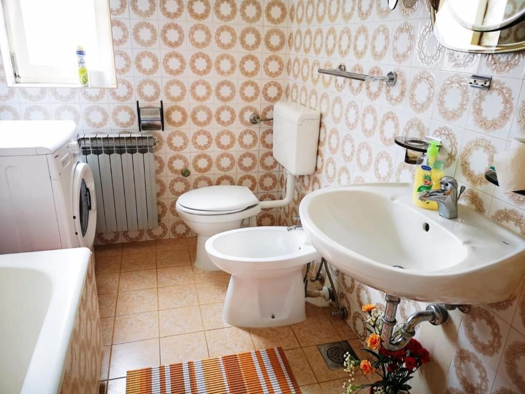 A bathroom with a toilet, bidet, sink, and washing machine.