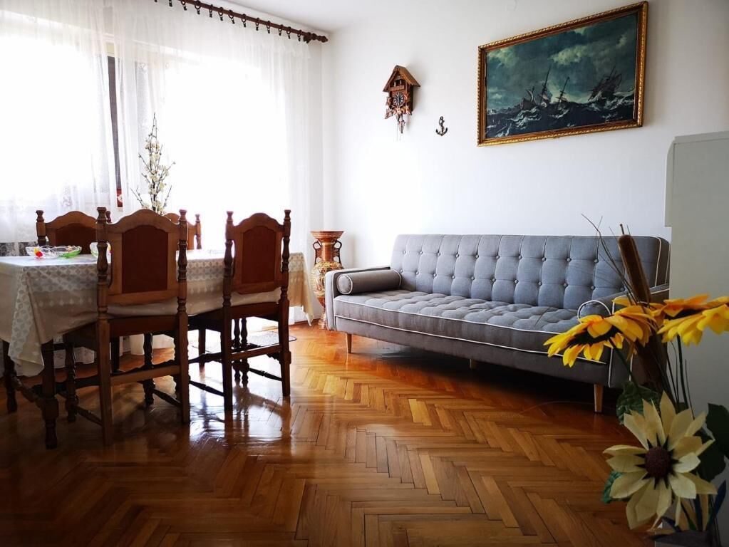 Un comedor con una mesa y sillas de madera, un sofá gris y un cuadro en la pared.