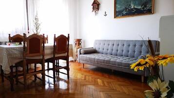 Un comedor con una mesa y sillas de madera, un sofá gris y un cuadro en la pared.