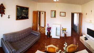 Una sala de estar con sofá, televisión, chimenea y puerta que da a otra habitación.