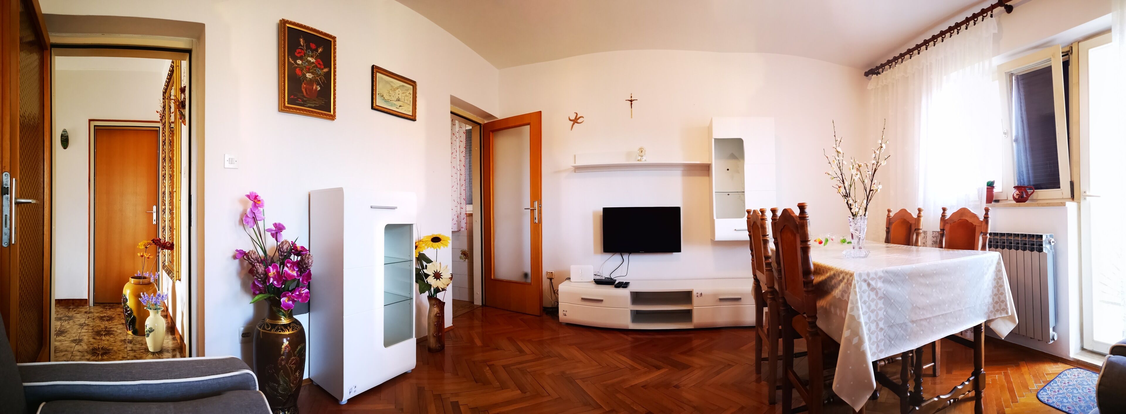 Un soggiorno con televisore, mobili in legno e tavolo da pranzo.