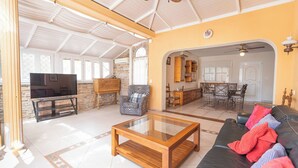 A spacious living area with a television, a sofa, and a coffee table. There is a dining area with a table and chairs. - Nice 3 Bedroom Villa in El Duque  (Costa Adeje)