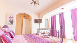 A bedroom with a bed, a TV, and purple curtains. - Nice 3 Bedroom Villa in El Duque  (Costa Adeje)