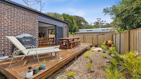 Enjoy al fresco dining and relaxation on the patio, featuring a barbecue grill, lounge chair, and dining table.