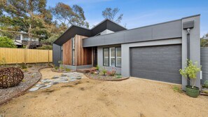 Stunning two-story home with a minimalist design, featuring a well-maintained front yard and a small garden area.