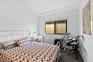 A bedroom with a bed, a desk, a chair, a window, and a drum set. - McMillan Escape (Anglesea)