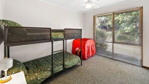 A room with bunk beds, a red play tent, a ceiling fan, and a window with blinds. - Oasis on Weir (Anglesea)