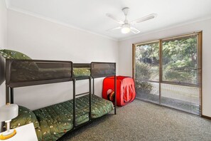 Ein Zimmer mit Etagenbetten, einem roten Spielzelt, einem Deckenventilator und einem Fenster mit Jalousien.